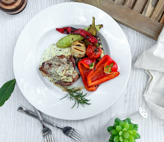 Carne frita en salsa cremosa con verduras al horno.