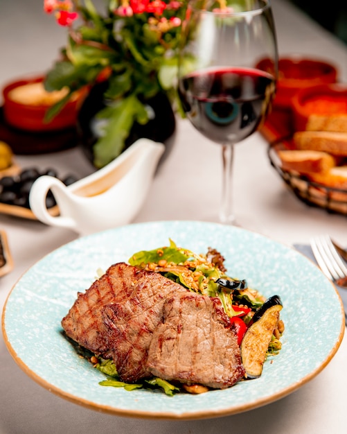 Carne frita servida con berenjenas y tomates.