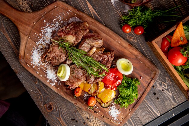 Carne frita servida con vegetales a la parrilla cebolla y ramita de romero