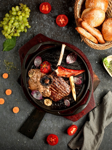 Carne frita con verduras y champiñones en una sartén de aluminio.