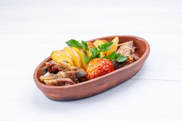 Carne frita con verduras y ciruelas al horno dentro de la placa marrón en la mesa de luz, comida plato de carne cena