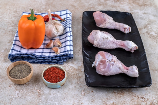 Foto gratuita carne de muslos de pollo sin cocer con verduras en una placa oscura