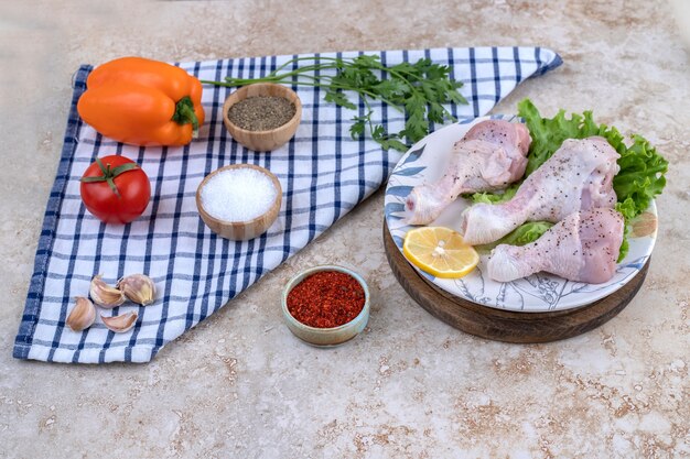 Carne de muslos de pollo sin cocer con verduras sobre una tabla de madera