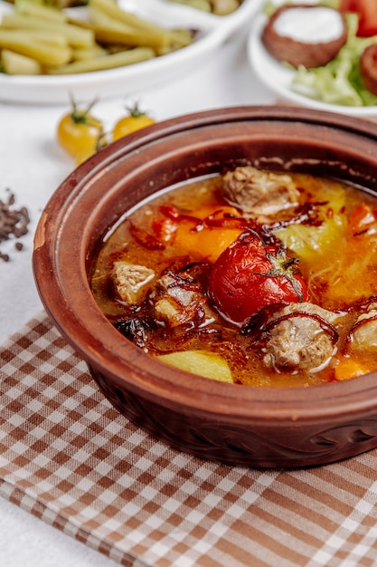 Carne con papas y tomates en una olla de barro