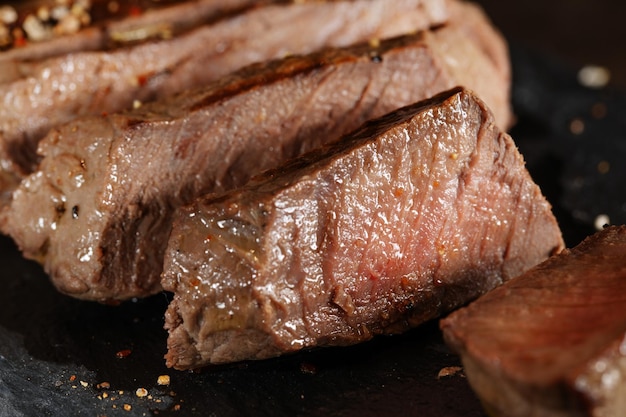 Carne a la parrilla cocida frita con especias cortadas en rodajas servidas en pizarra oscura Primer plano