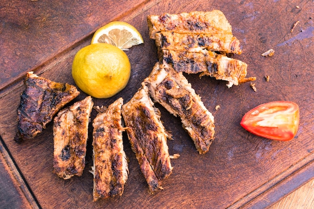 Carne a la parrilla y rodajas de tomate limón en mesa