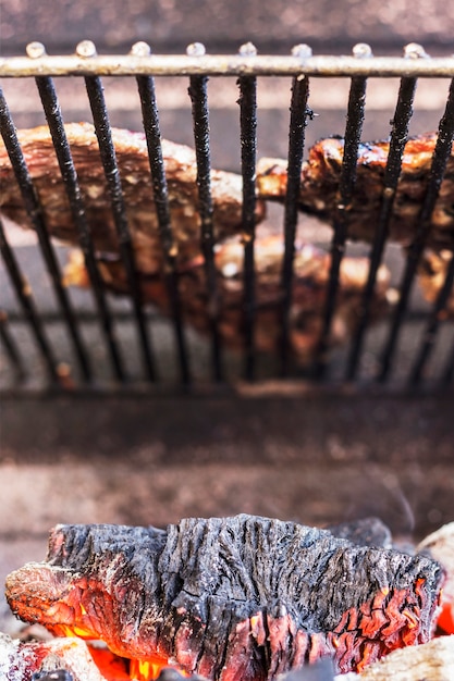 Carne a la parrilla sobre el carbón quemado en la barbacoa