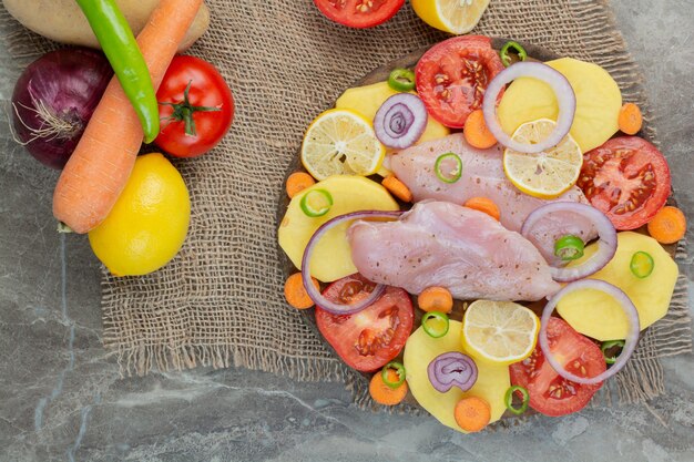 Carne de pollo cruda con verduras y especias sobre fondo de mármol. Foto de alta calidad