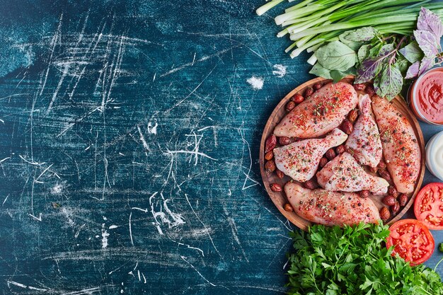 Carne de pollo con especias rojas y verduras alrededor.