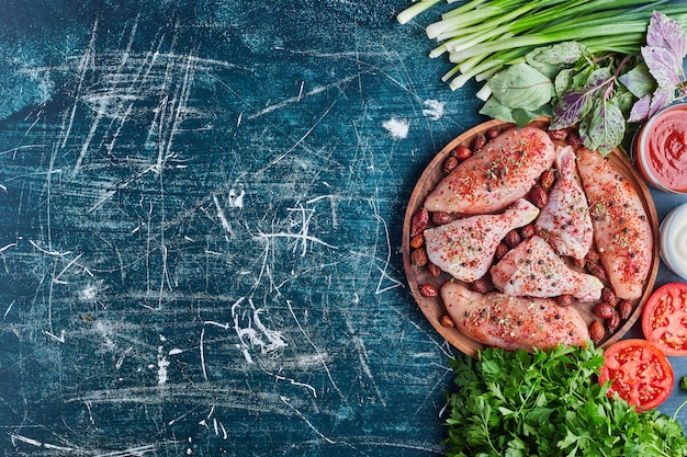 Carne de pollo con especias rojas y verduras alrededor.