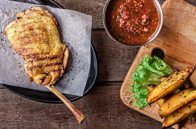 Carne de pollo frita en el hueso, gajos de papa, lechuga