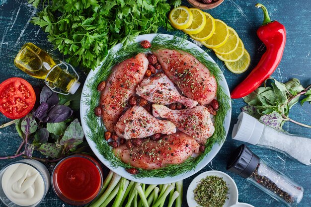 Carne de pollo con hierbas y verduras alrededor.