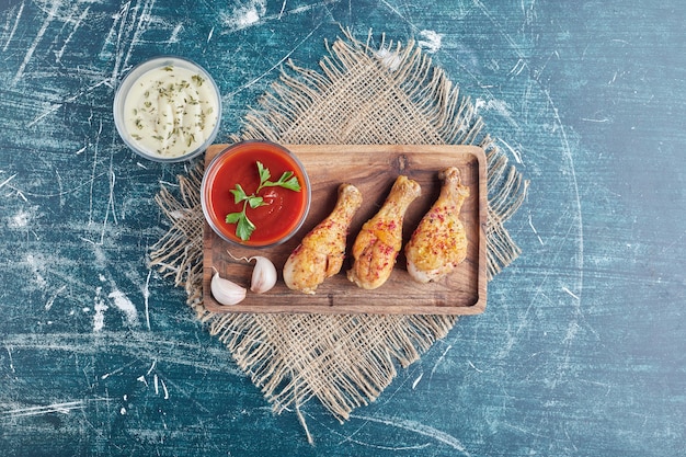 Foto gratuita carne de pollo picante en una tabla de madera con salsas.