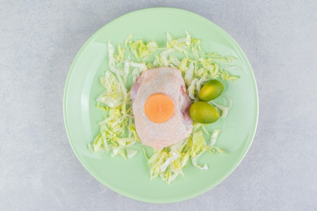 Carne de pollo en las verduras con kumquat y zanahoria en el plato, sobre la superficie blanca