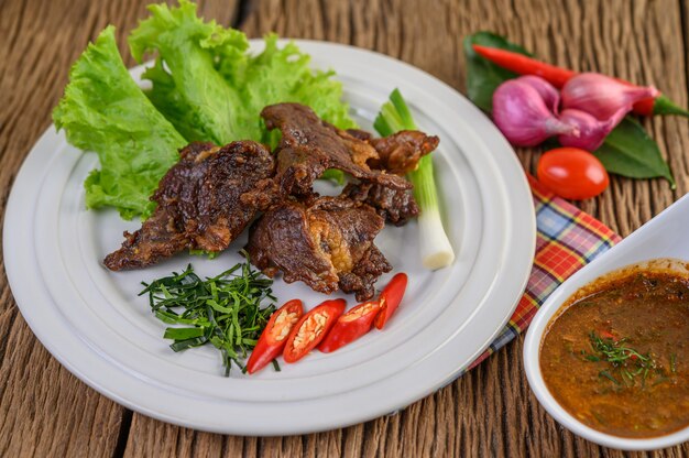 Carne de res frita comida tailandesa en un plato blanco con cebolleta, hojas de lima kaffir, chiles, ensalada, cebolla roja y tomates.