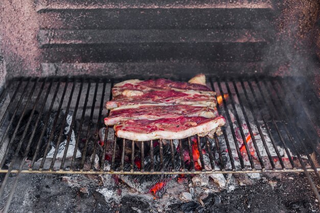 Carne de vaca sin cocinar a la parrilla sobre carbón quemado