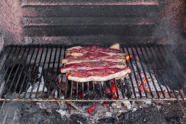 Carne de vaca sin cocinar a la parrilla sobre carbón quemado