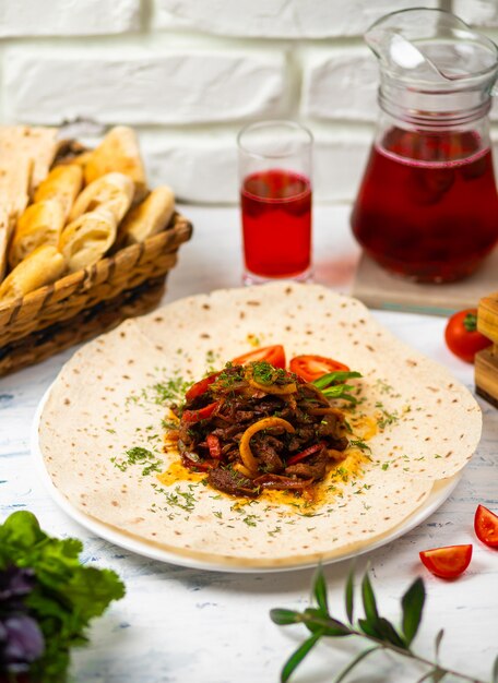 Carne y verduras asadas con hierbas en un plato blanco con verduras de pan y una copa de vino