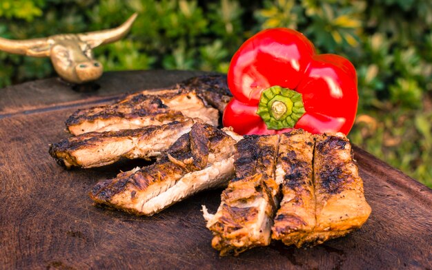 Carnes a la brasa y pimiento rojo sobre mesa.