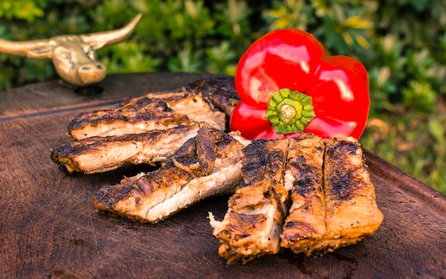 Carnes a la brasa y pimiento rojo sobre mesa.