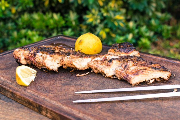 Carnes a la brasa y rodajas de limón sobre mesa.