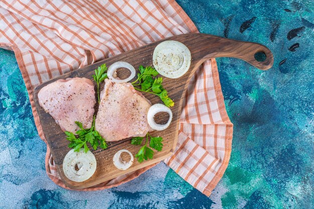 Carnes de pollo en una tabla para cortar sobre el paño de cocina