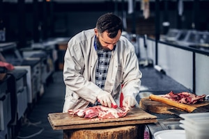 Foto gratuita carnicero barbudo vestido con una camisa de lana corta carne de tocino fresco.