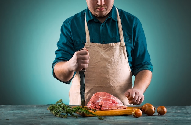 Carnicero cortando carne de cerdo en la cocina