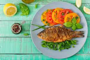 Foto gratuita carpa de pescado frito y ensalada de verduras frescas en la mesa de madera. endecha plana. vista superior