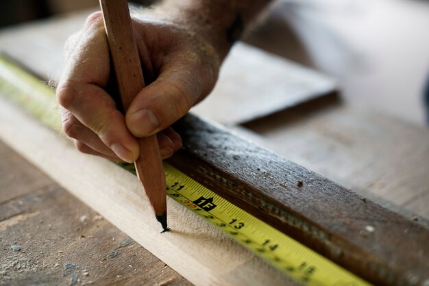 Carpenter con lápiz y cinta de medición en madera