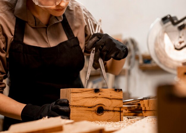 Carpintero femenino en la oficina midiendo la pieza de madera