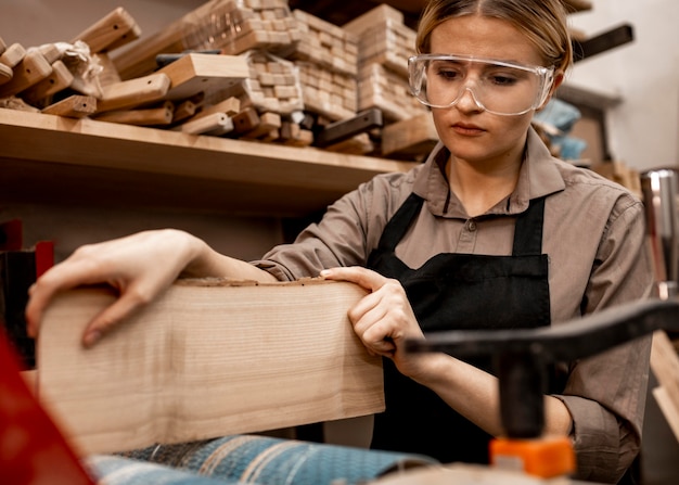 Foto gratuita carpintero femenino con trozo de madera en el trabajo