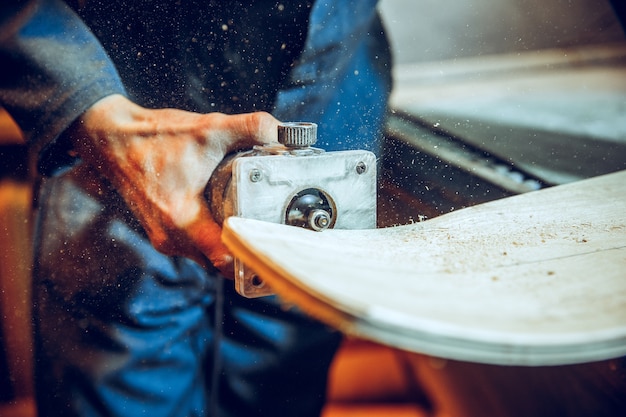 Carpintero con sierra circular para cortar tablas de madera. Detalles de construcción de trabajador masculino o hombre práctico con herramientas eléctricas