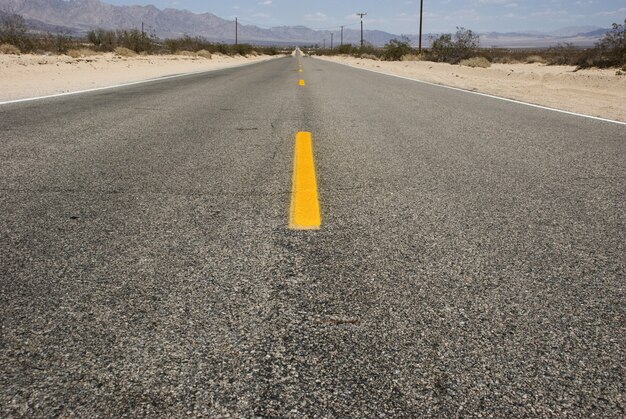 Carretera asfaltada larga y recta a través del paisaje desértico del Valle de la Muerte