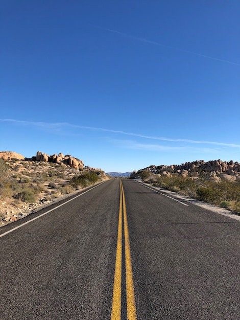 Carretera asfaltada con líneas amarillas bajo un cielo azul claro