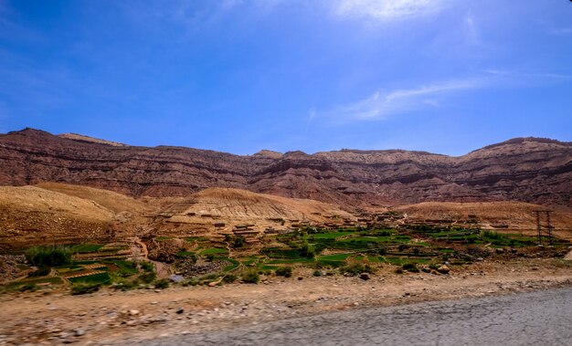 Carretera cerca de los campos de hierba con montañas de arena en la distancia y un cielo azul