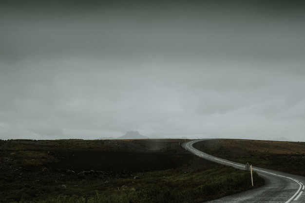 Carretera larga con curvas en medio de un campo verde en Islandia