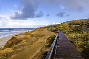 Foto gratuita carretera de madera en el acantilado rojo cerca de la playa en sylt, alemania