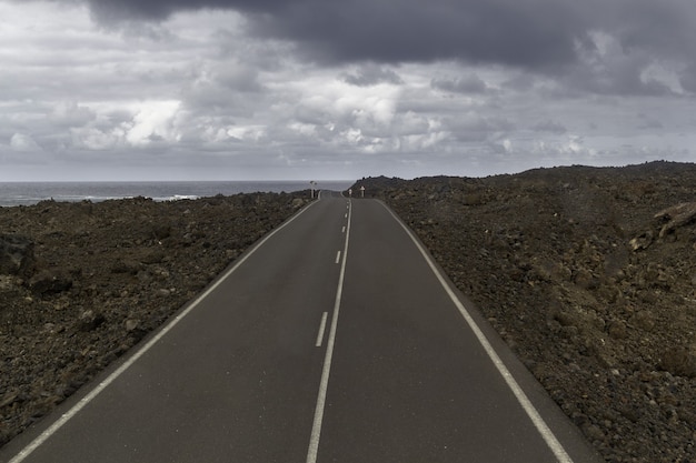 Carretera rodeada de colinas bajo un cielo nublado en el Parque Nacional de Timanfaya en España