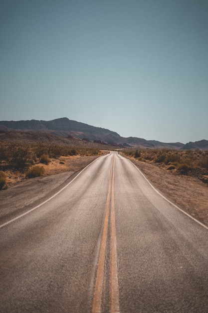 Carretera vacía del desierto estrecho con hermosas colinas en el fondo