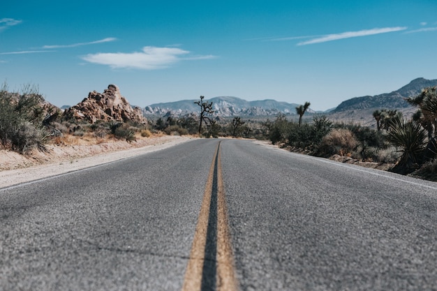 Carretera vacía con montañas en la distancia bajo un cielo azul