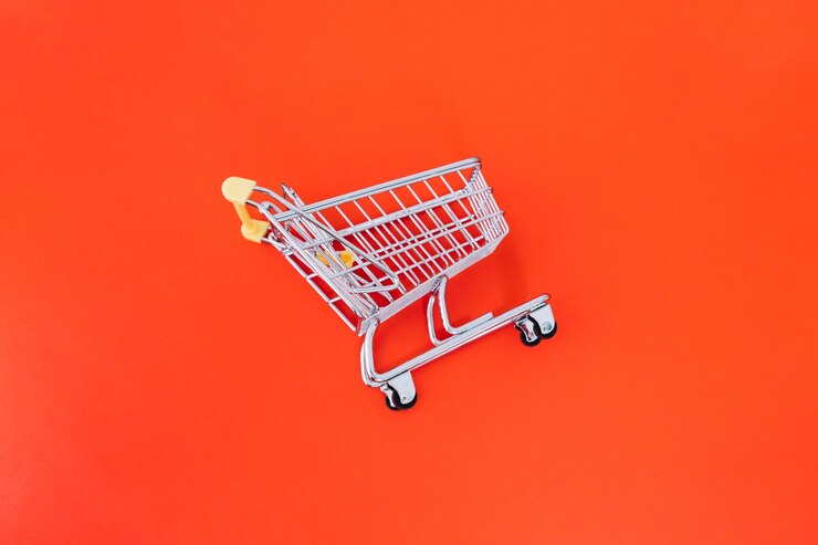 Foto gratuito el carrito de compras en fondo naranja