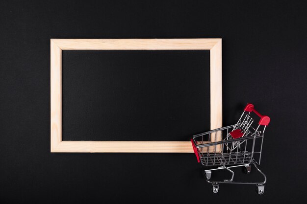 Carrito de compras frente a pizarra en blanco