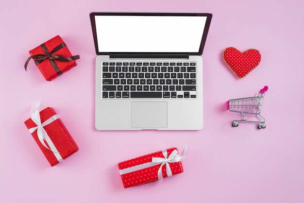 Foto gratuita carrito de compras de juguete y corazón cerca de laptop y regalos.