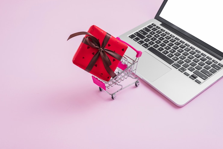 Foto gratuito carrito de compras y regalo cerca de portátil moderno.
