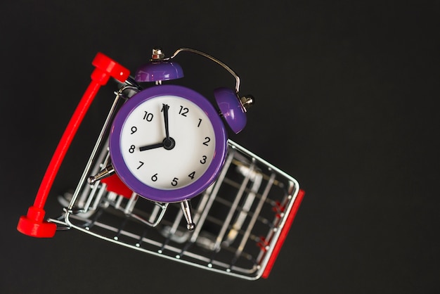 Carrito de supermercado con reloj despertador.