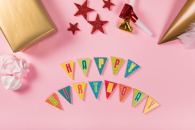 Foto gratuito carta de feliz cumpleaños con artículos de fiesta y zephyrs sobre fondo rosa