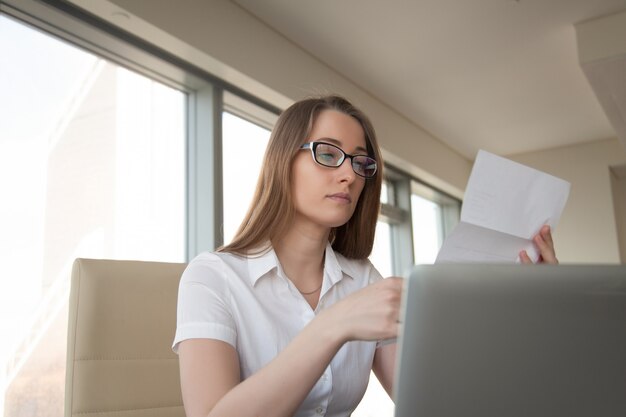 Carta joven de la lectura de la empresaria en el lugar de trabajo