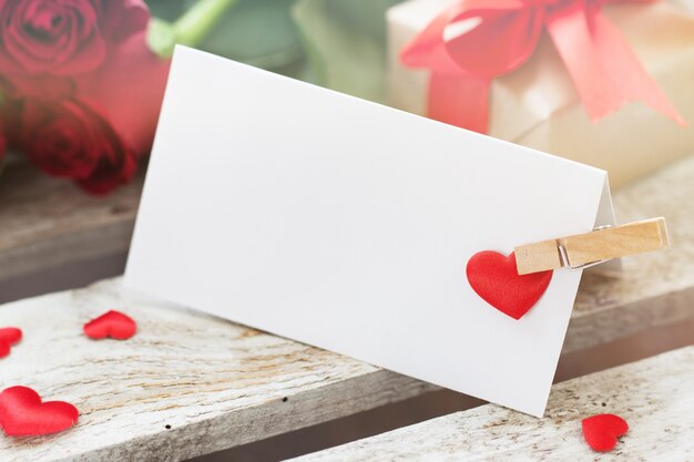 Foto gratuita carta con una pinza y un corazón rojo con rosas al lado