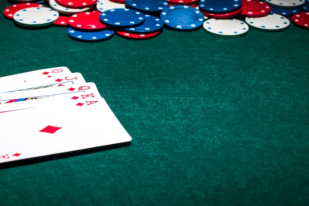 Foto gratuita cartas de juego de escalera real y fichas de casino en el fondo de póquer verde